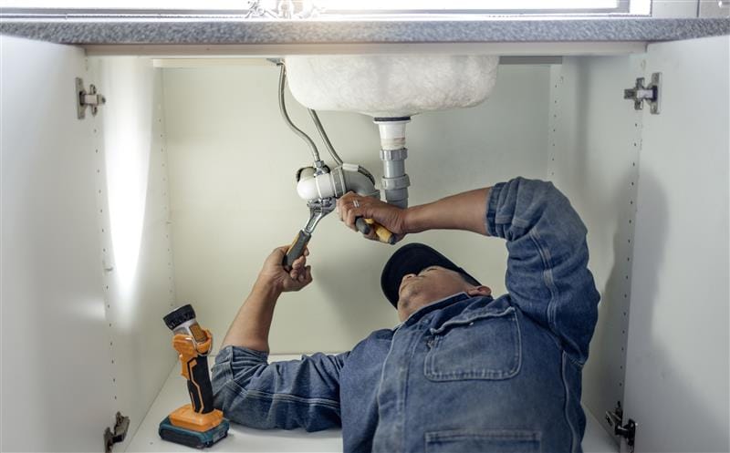 Plumber repairing pipes beneath a bathroom sink in Smyrna