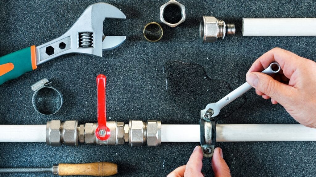 Plumber repairing a pipe valve with an adjustable wrench in Smyrna