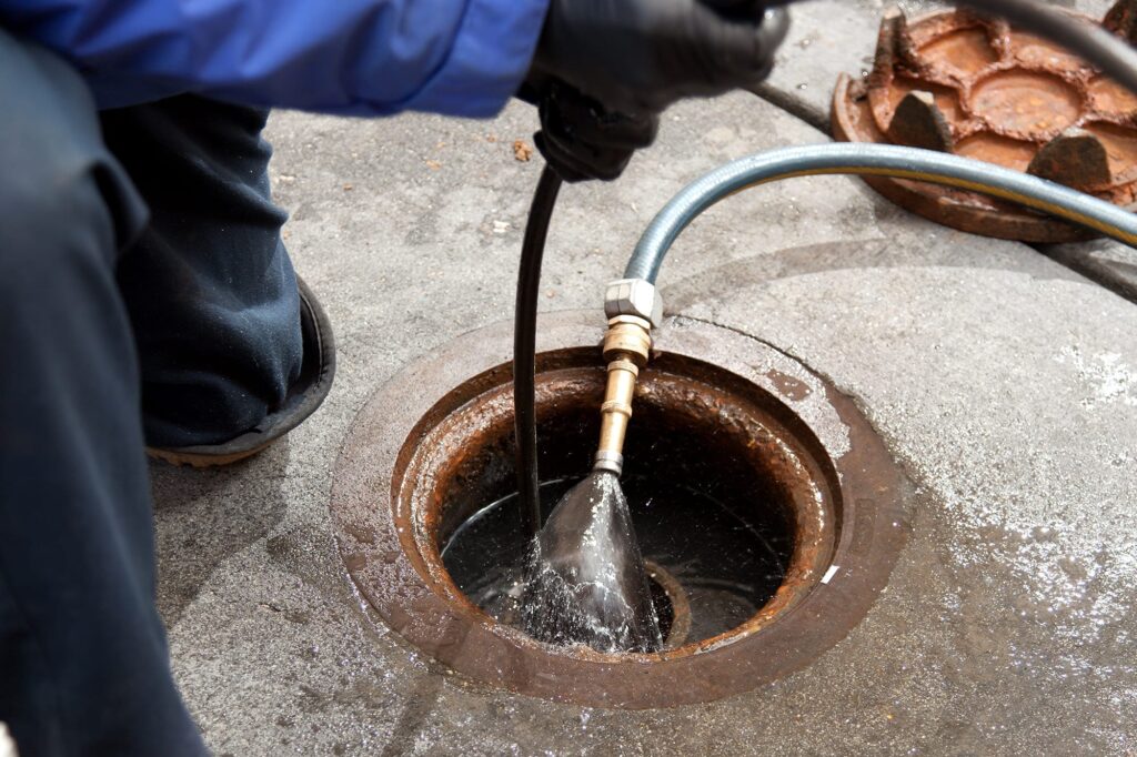 Plumber hydro jetting a sewer line through a manhole in Smyrna