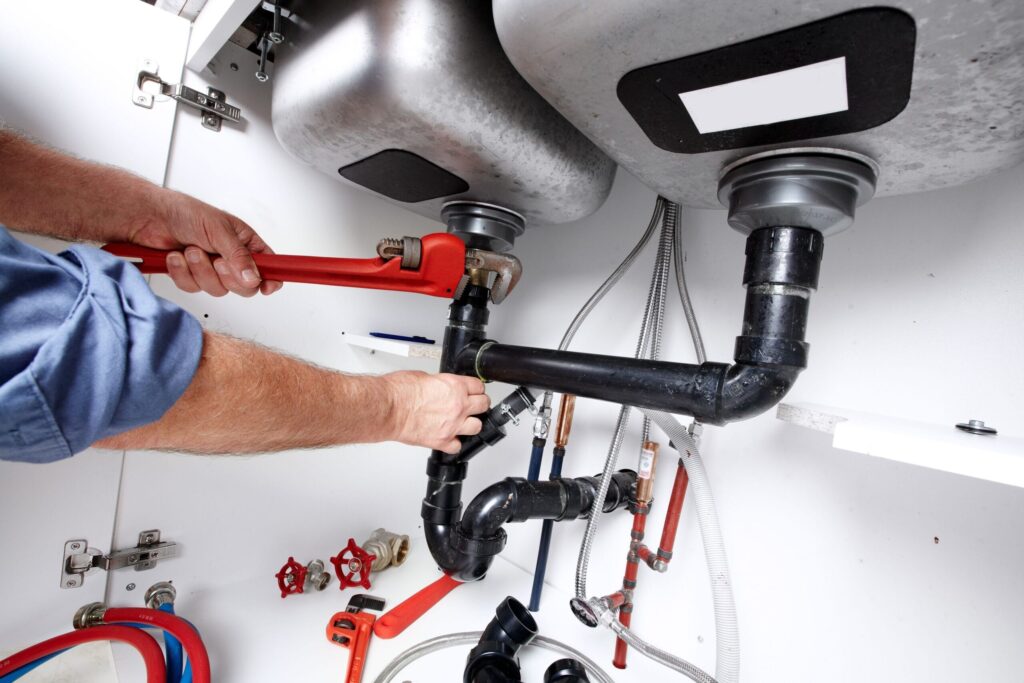 Plumber repairing drain pipes beneath a kitchen sink in Smyrna
