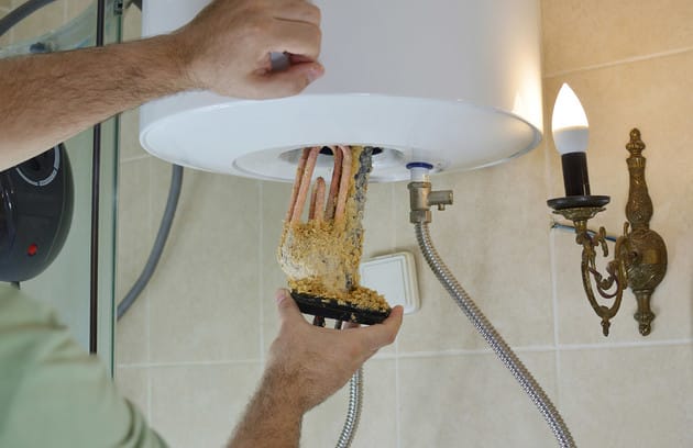 Technician removing mineral buildup from a water heater in Smyrna