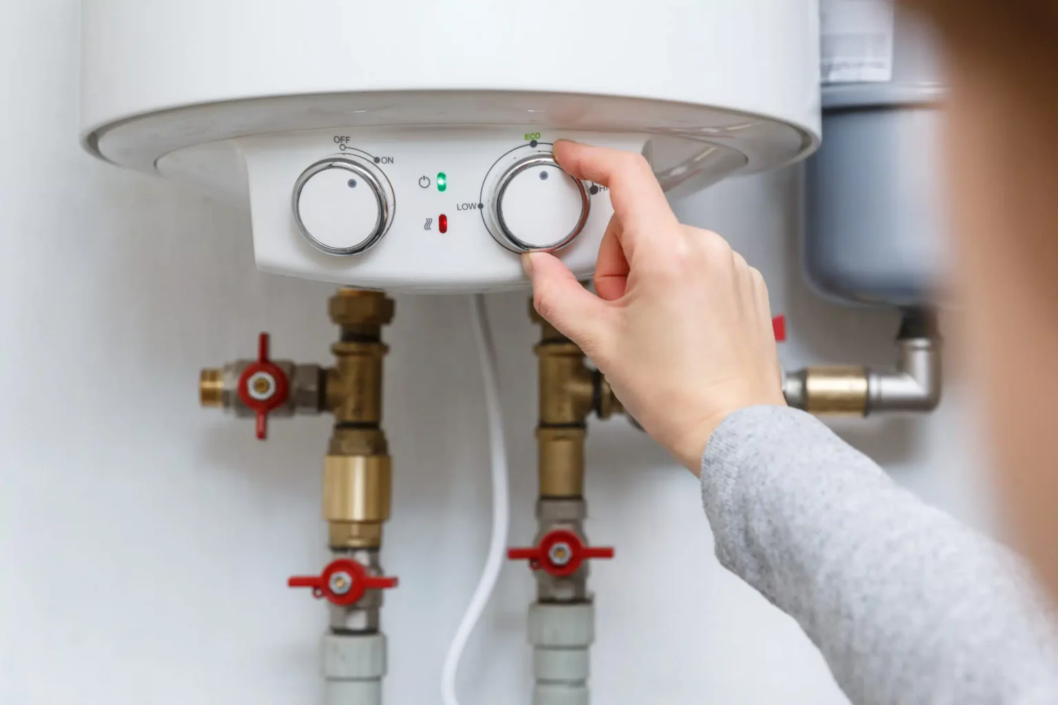 Homeowner adjusting the temperature controls on a water heater in Smyrna